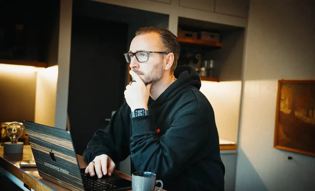 Patrick Lenz sitzt nachdenklich im Homeoffice am Laptop